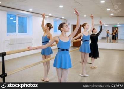 Master and young ballerinas exercise at the barre in class. Ballet school, female dancers on choreography lesson, girls practicing grace dance. Master and ballerinas, exercise at barre in class