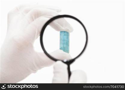 master checks aquamarine crystal with magnifier on white background