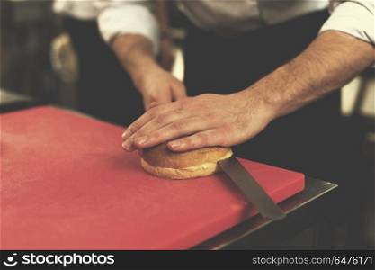 master chef hands cutting rolls for a burger in the rastaurant kitchen. chef hands cutting rolls for burger