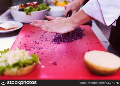 master chef hands cutting salad for a burger in the rastaurant kitchen. chef hands cutting salad for burger