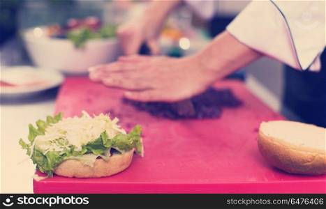 master chef hands cutting salad for a burger in the rastaurant kitchen. chef hands cutting salad for burger