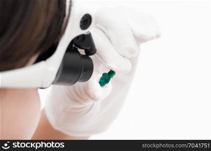 master in head-mounted lens checks dioptase crystal on whie background