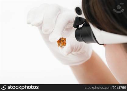 master in head-mounted lens checks spessartine crystals on whie background