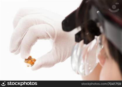 master in head wearing magnifying glasses checks spessartine crystals on whie background
