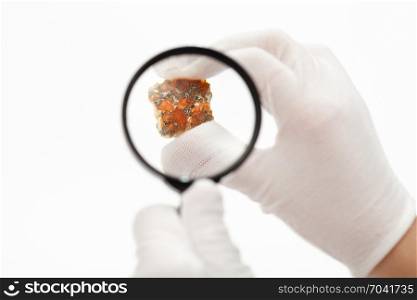 master inspects spessartine garnets with magnifier on white background