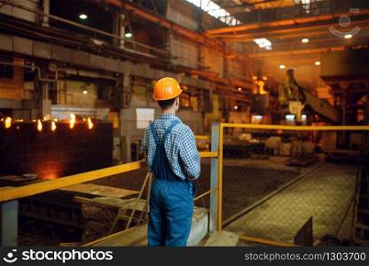 Master looks on steelmaking process in furnace, steel factory, metallurgical or metalworking industry, industrial manufacturing of metal production on mill. Master looks on steelmaking process in furnace