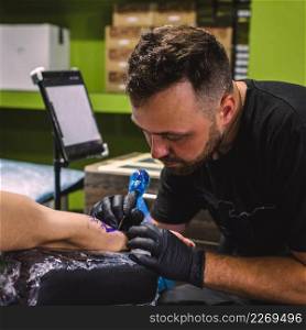 master making tattoo with needle machine
