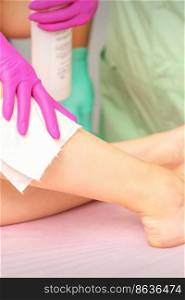 Master of depilation wipes female feet with white napkin preparing for the procedure of hair removal. Master of depilation wipes female feet with white napkin preparing for the procedure of hair removal.