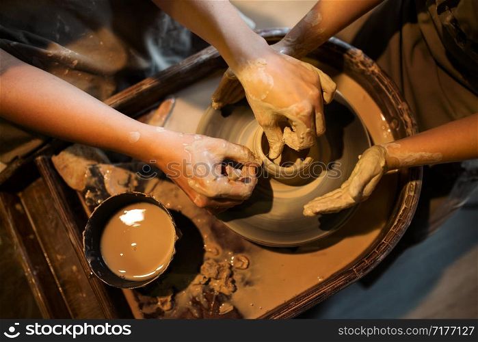 Master potter teaches the child to work on the Potter&rsquo;s wheel. Close up shot.. Master potter teaches the child to work on the Potter&rsquo;s wheel. Close up shot