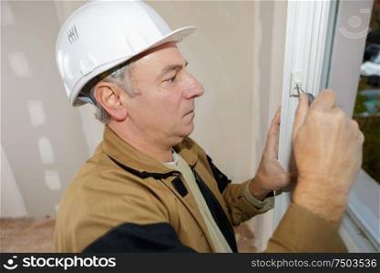 master with a screwdriver sets fittings on the window