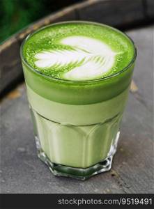 Matcha latte green milk foam cup on wood barrel