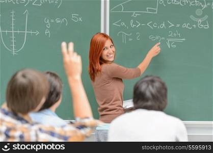 Math lesson student write on green chalkboard looking at classmates