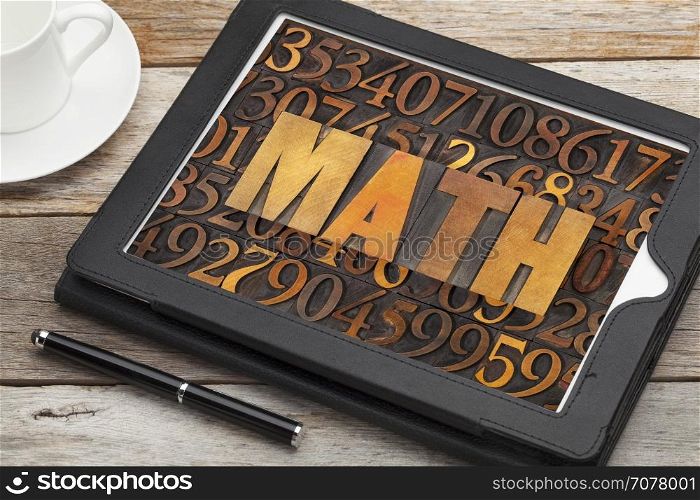 math (mathematics) word in vintage letterpress wood type against number background on a tablet screen with a cup of coffee