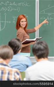 Mathematics student girl pointing on chalkboard looking at classmates