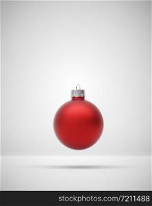 Matte gold crimson Christmas bauble levitating on a light grey background for seasonal Holiday celebrations and themes