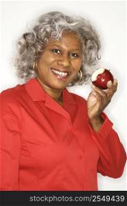 Mature adult African American female holding half eaten apple smiling.