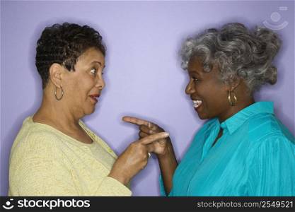 Mature adult African American females pointing at eachother.