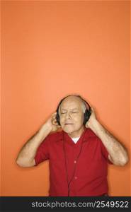 Mature adult Caucasian male listening to headphones.,