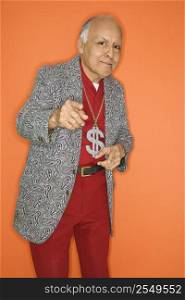 Mature adult Caucasian male wearing money sign necklace and pointing.