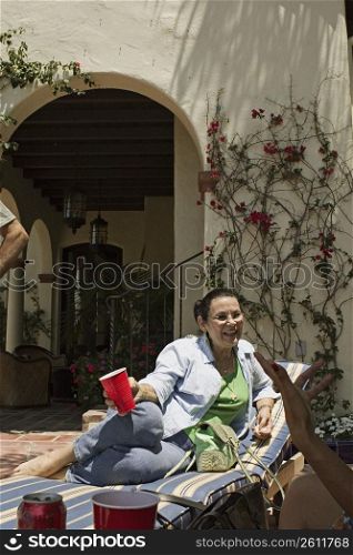 Mature adult woman conversing while lying on pool chair