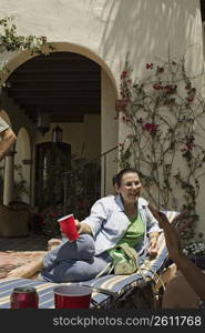 Mature adult woman conversing while lying on pool chair