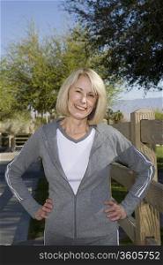 Mature adult woman stands smiling in tracksuit with hands on hips