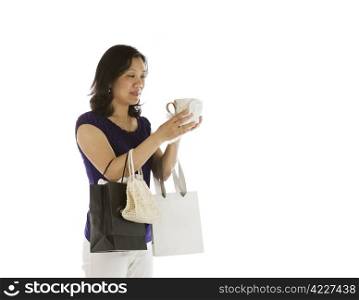 Mature asian women inspecting new coffee mug on white background