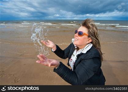 Mature attractive woman in sunglasses relaxing at the Baltic sea in autumn day.