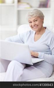 Mature attractive woman on the couch with a laptop