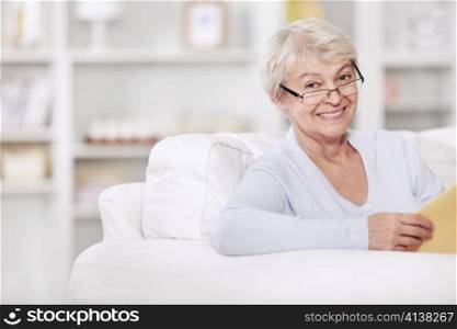 Mature attractive woman with a book on the couch