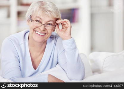 Mature attractive woman with glasses on the sofa