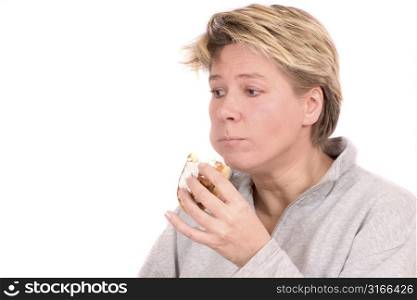 Mature blond woman looking a bit guilty for eating a sweet bun