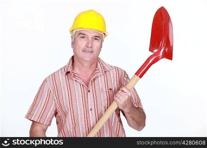 mature bricklayer holding shovel against studio background