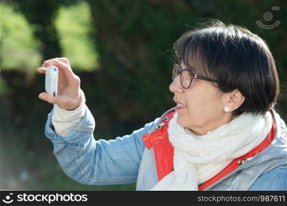 mature brunette woman using a smartphone, outdoors