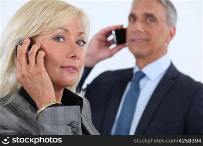 Mature business couple using cellphones
