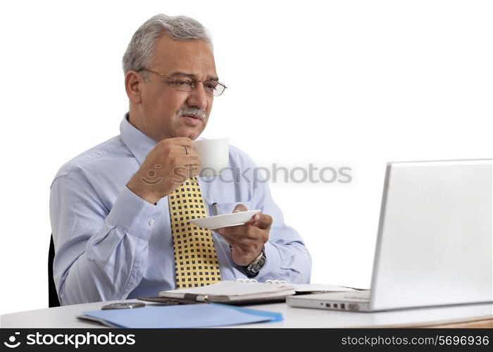 Mature business man looking at laptop with cup of coffee