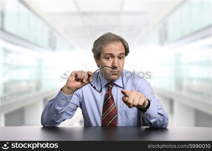 mature business man on a desk pointing at the office
