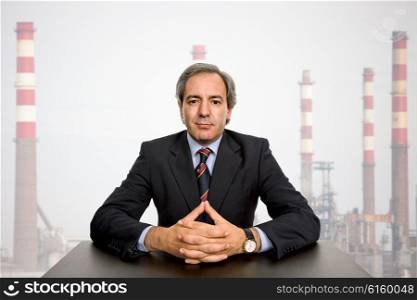 mature business man on a desk with a factory behind