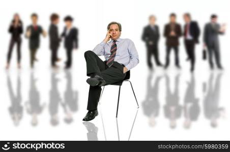 mature business man seated on a chair with people in the back