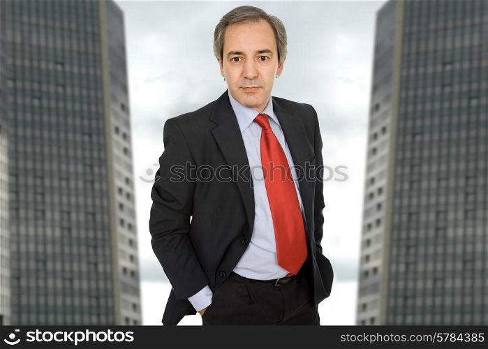 mature business man standing with two office building behind