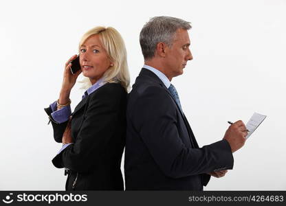 mature businessman and female partner standing back to back