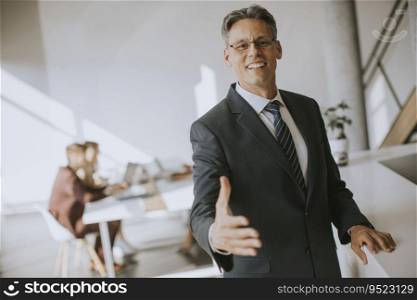 Mature businessman approaching  and offering for hand for handshake in the office
