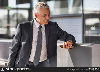 Mature businessman checking time on his wristwatch in airport
