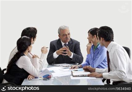 Mature businessman conversing with staff in meeting