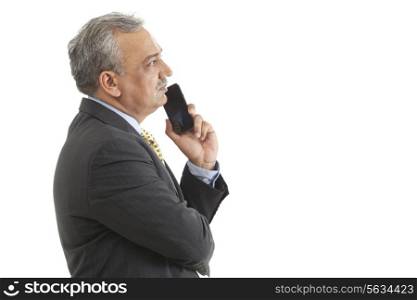 Mature businessman day dreaming with mobile phone