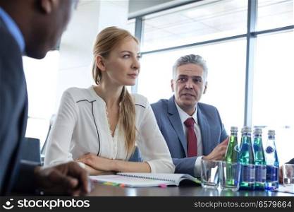 Mature businessman discussing with colleagues at table in board room