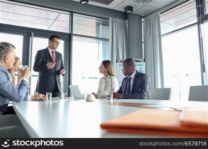 Mature businessman discussing with colleagues in meeting room