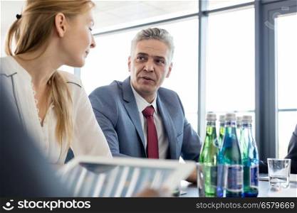 Mature businessman discussing with female colleague in board room
