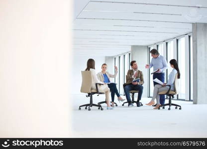 Mature businessman discussing with team sitting on chair in new office