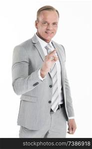 Mature businessman doing ok sign, isolated over white background. Mature businessman doing ok sign